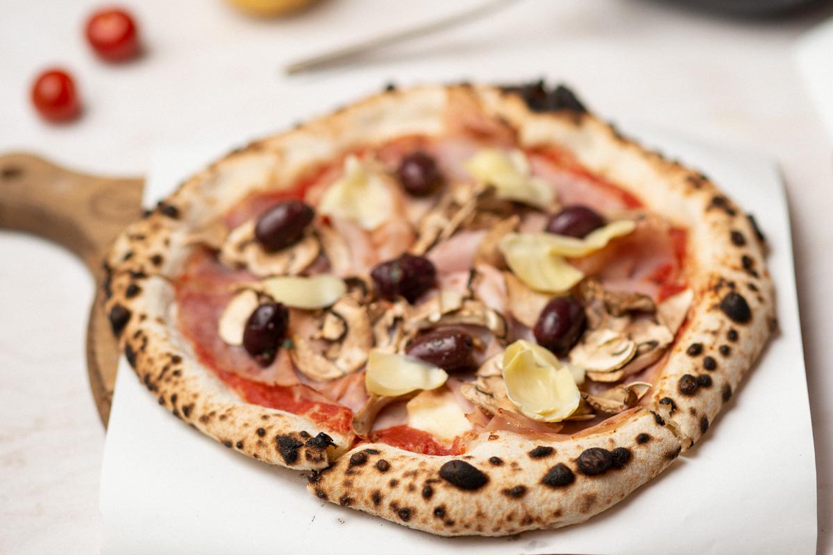 Capriciosa pizza on a wooden peel — Viva La Pizza oven